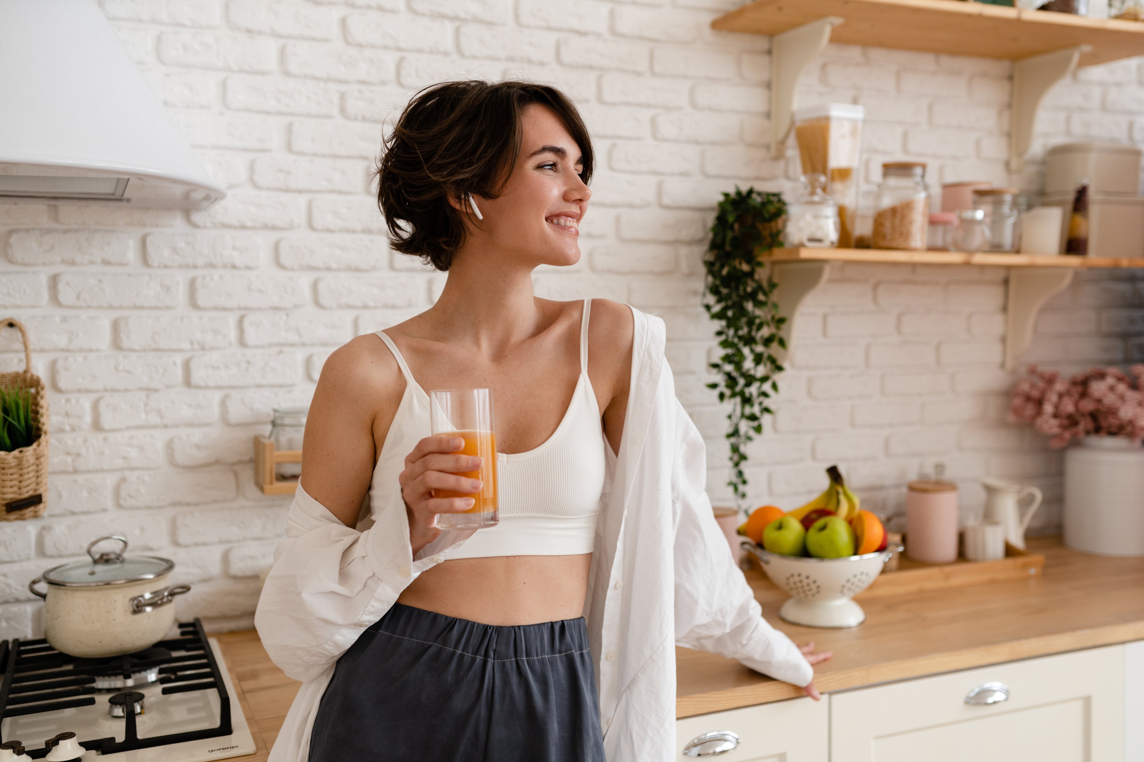 Woman in a kitchen holding a glass of orange juice with collagen